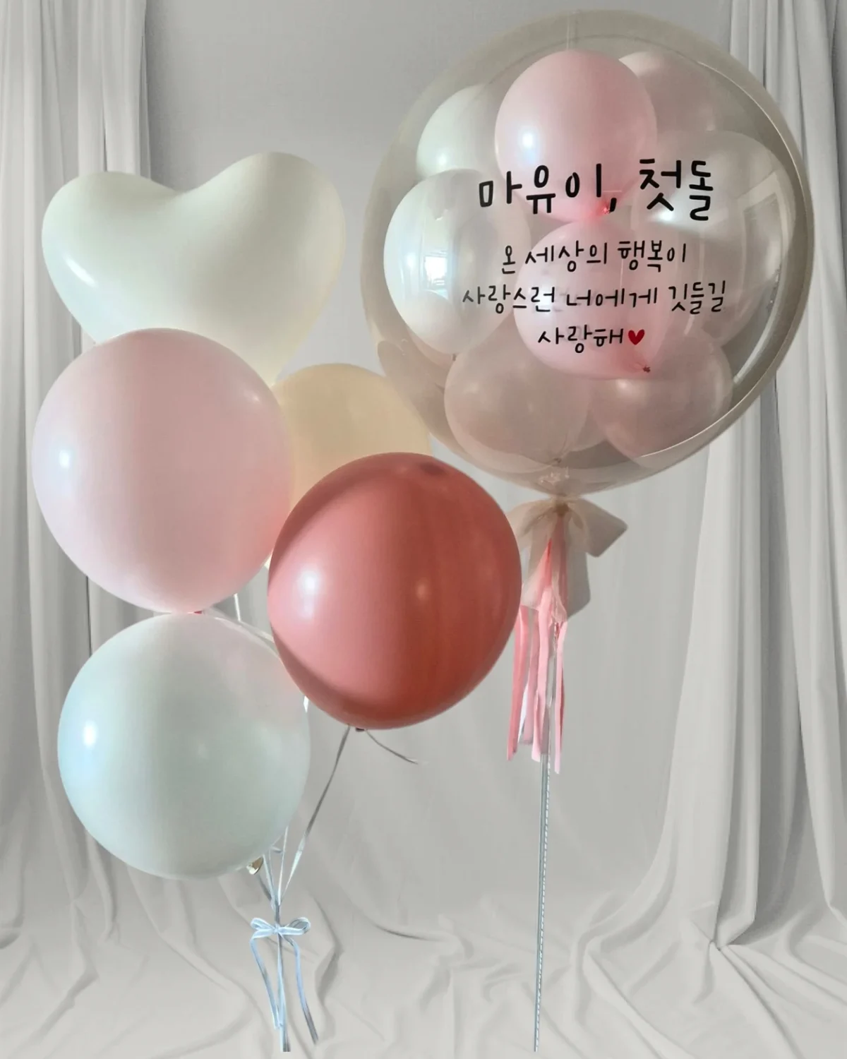 분홍색과 민트색 풍선에 첫돌 축하 문구를 넣은 제이러브플로르의 실제 제작 작품